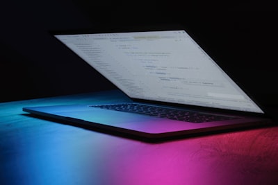 Open laptop with code on screen in neon lighting
